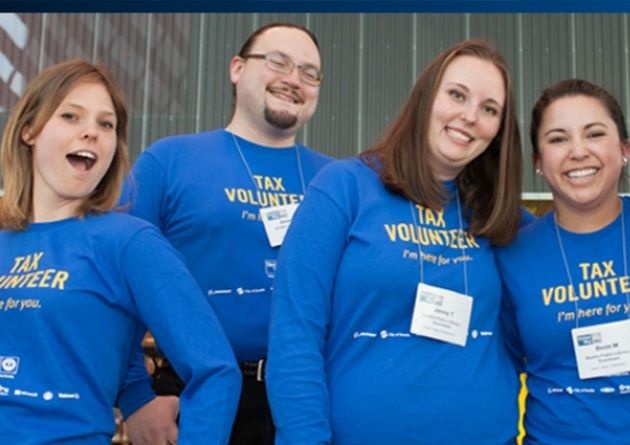 Four smiling people posing while wearing blue shirts that say "Tax Volunteer".